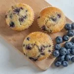Muffins aux bleuets avec des bleuets frais disposés sur une planche de bois,