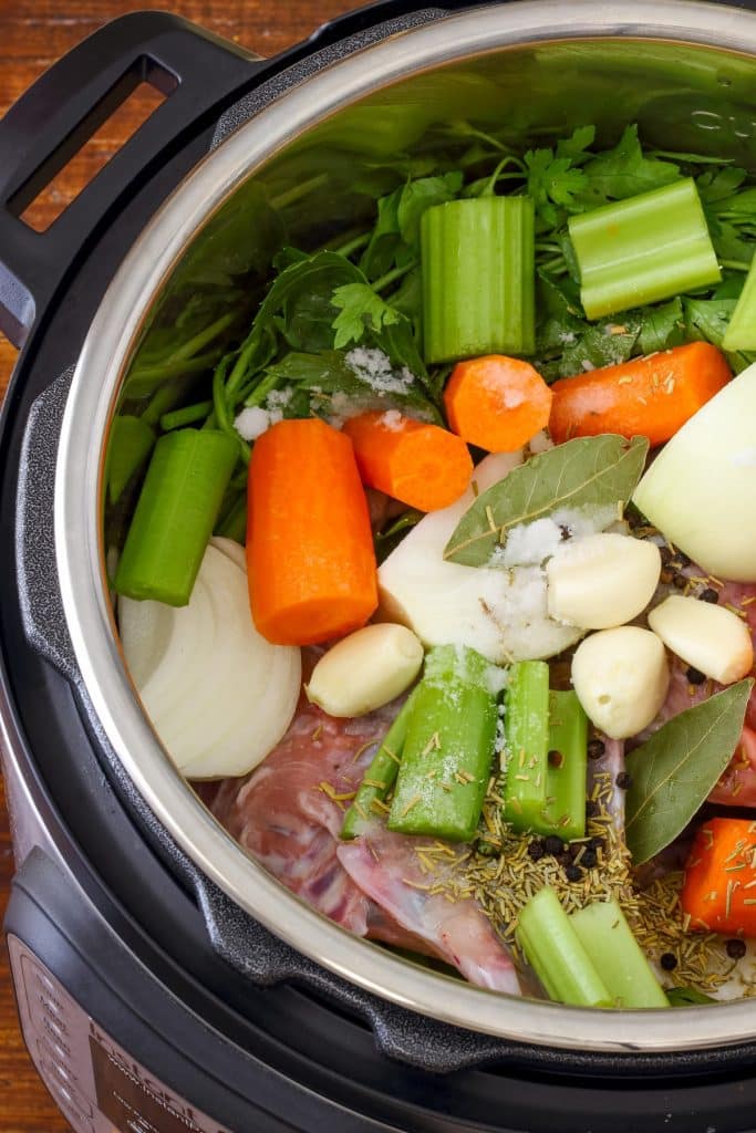 Volaille, légumes et aromates dans le récipient du multicuiseur pour faire un bouillon