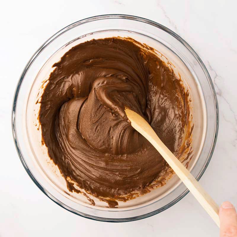 Pépites de chocolat fondus avec lait Eagle Brand qui sort du micro-ondes avec cuillère de bois pour mélanger