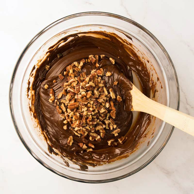 Mélange de fudge au chocolat avec l'ajout de vanille et de noix hachées et mélange avec une grosse cuillère de bois