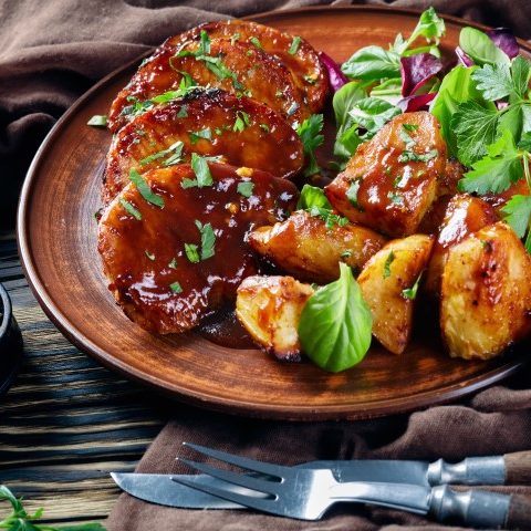 Côtelettes de porc avec sa sauce légèrement sucrée servi avec pommes de terre rôties et salade
