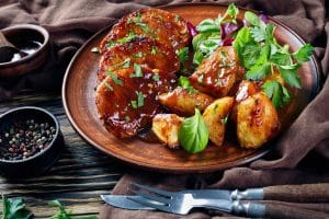 Côtelettes de porc avec sa sauce légèrement sucrée servi avec pommes de terre rôties et salade