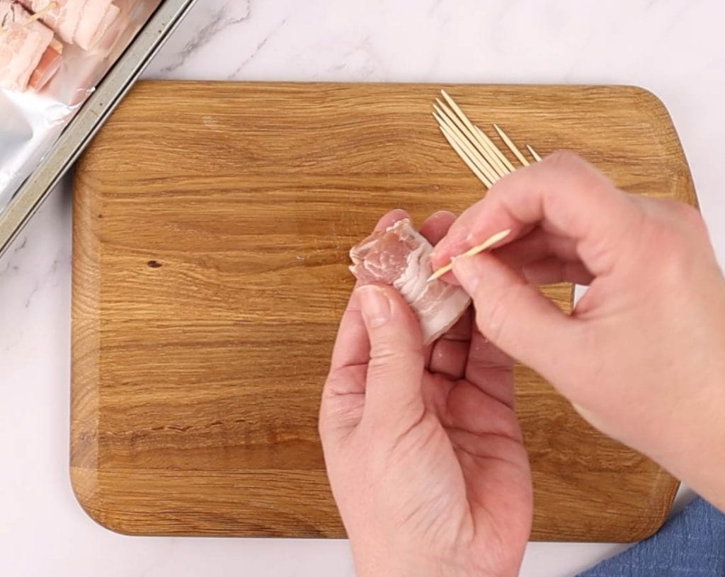 On attache le bacon sur la saucisse avec un cure-dent