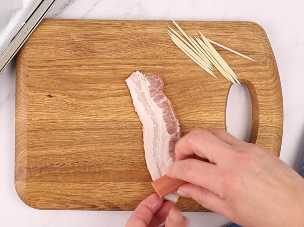 On enroule une demi-tranche de bacon autour d'un morceau de saucisse pour faire un hors-d'oeuvre