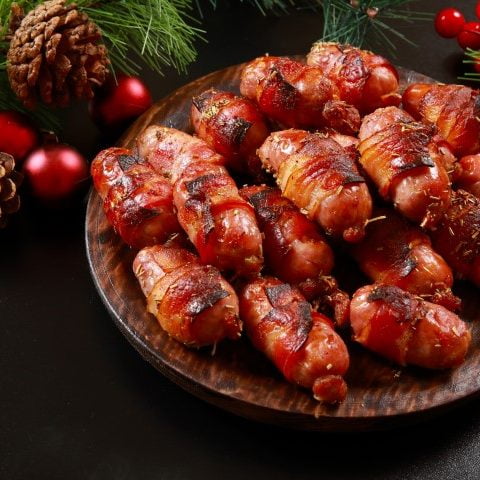 Saucisses enrobées de bacon cuites dans une assiette en bois avec décoration de Noël