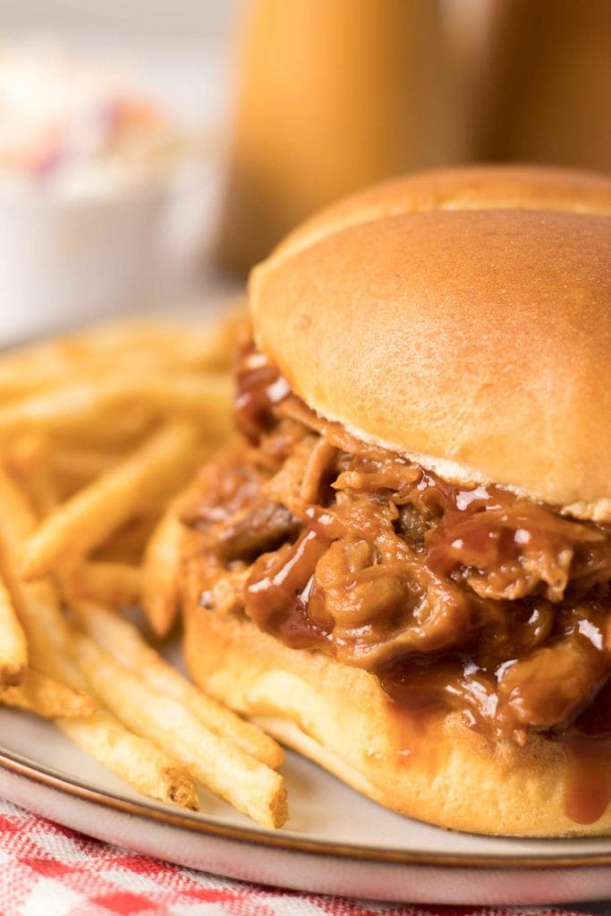 Sandwich au porc effiloché fait à la mijoteuse servi avec des frites et une salade de chou