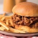 Porc effiloché tendre et juteux servi dans un pain hamburger grillé et accompagné de pommes de terre frites