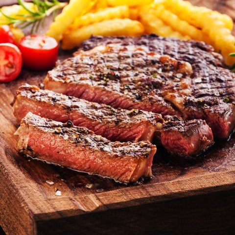 Steak mariné sur une planche servi avec pommes de terre frites