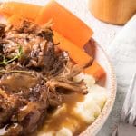 rôti de palette avec gravy, patates pilées et carotte dans une assiette