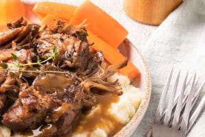 rôti de palette avec gravy, patates pilées et carotte dans une assiette