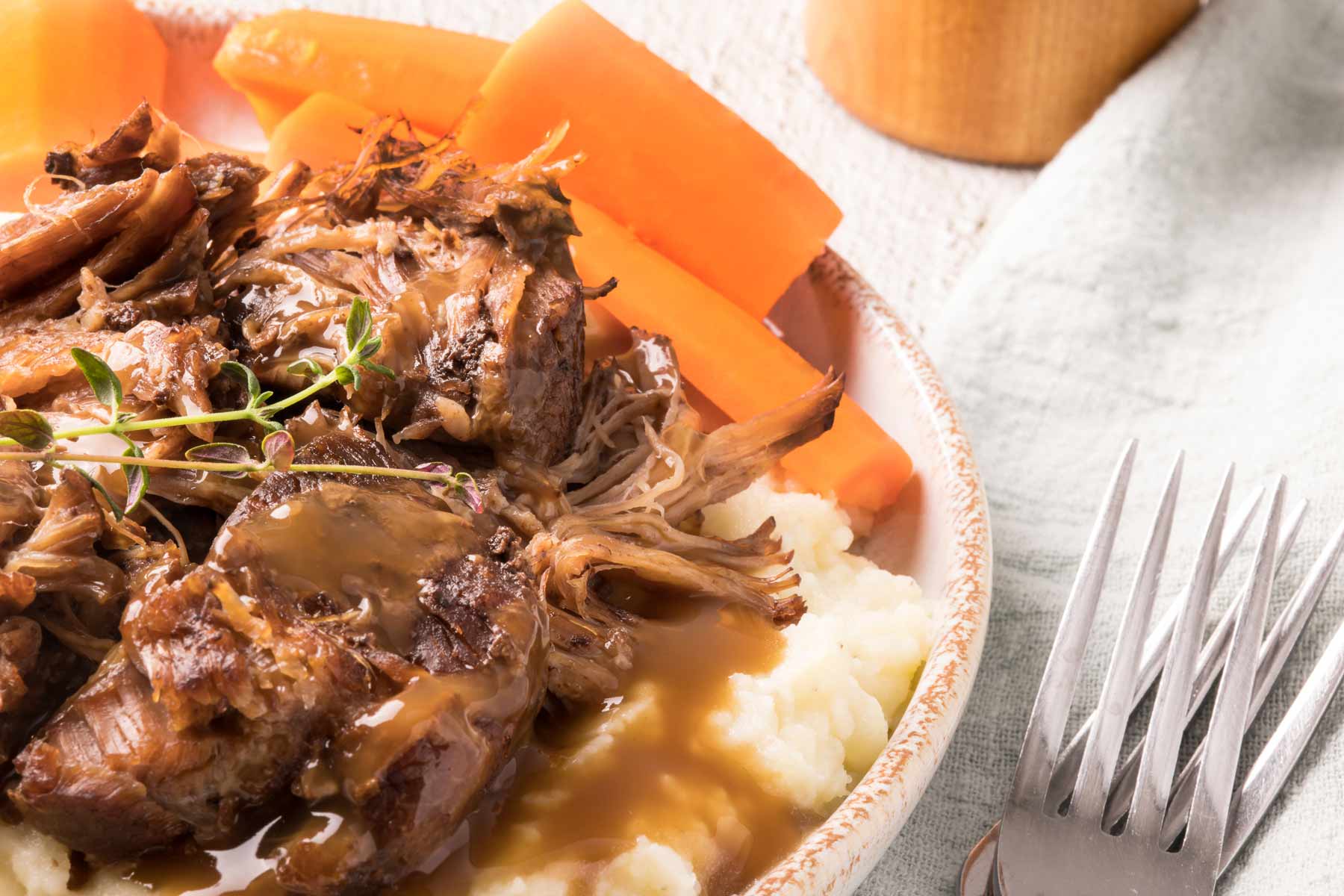 rôti de palette avec gravy, patates pilées et carotte dans une assiette