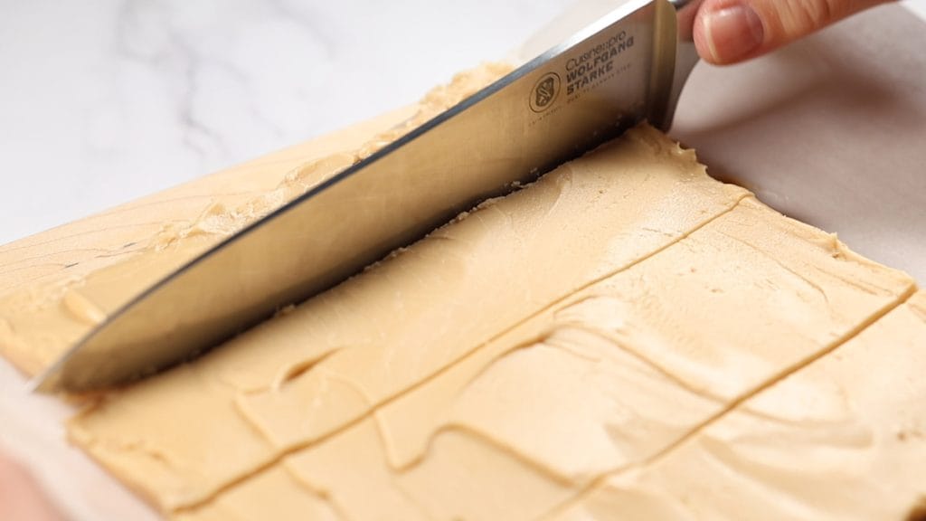 Coupe du sucre à la crème en carrés avec un couteau.