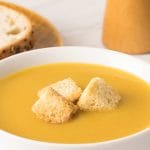crème de légumes maison servie dans deux bols blancs avec croûtons et petits pains