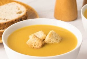 crème de légumes maison servie dans deux bols blancs avec croûtons et petits pains