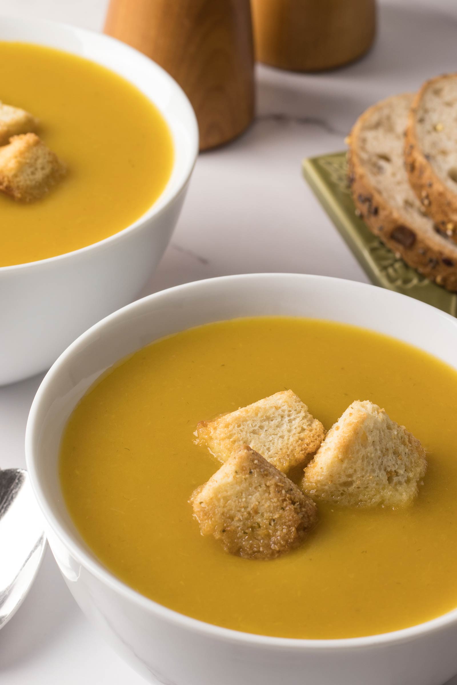 Deux bols de potage aux légumes avec croûtons et pains
