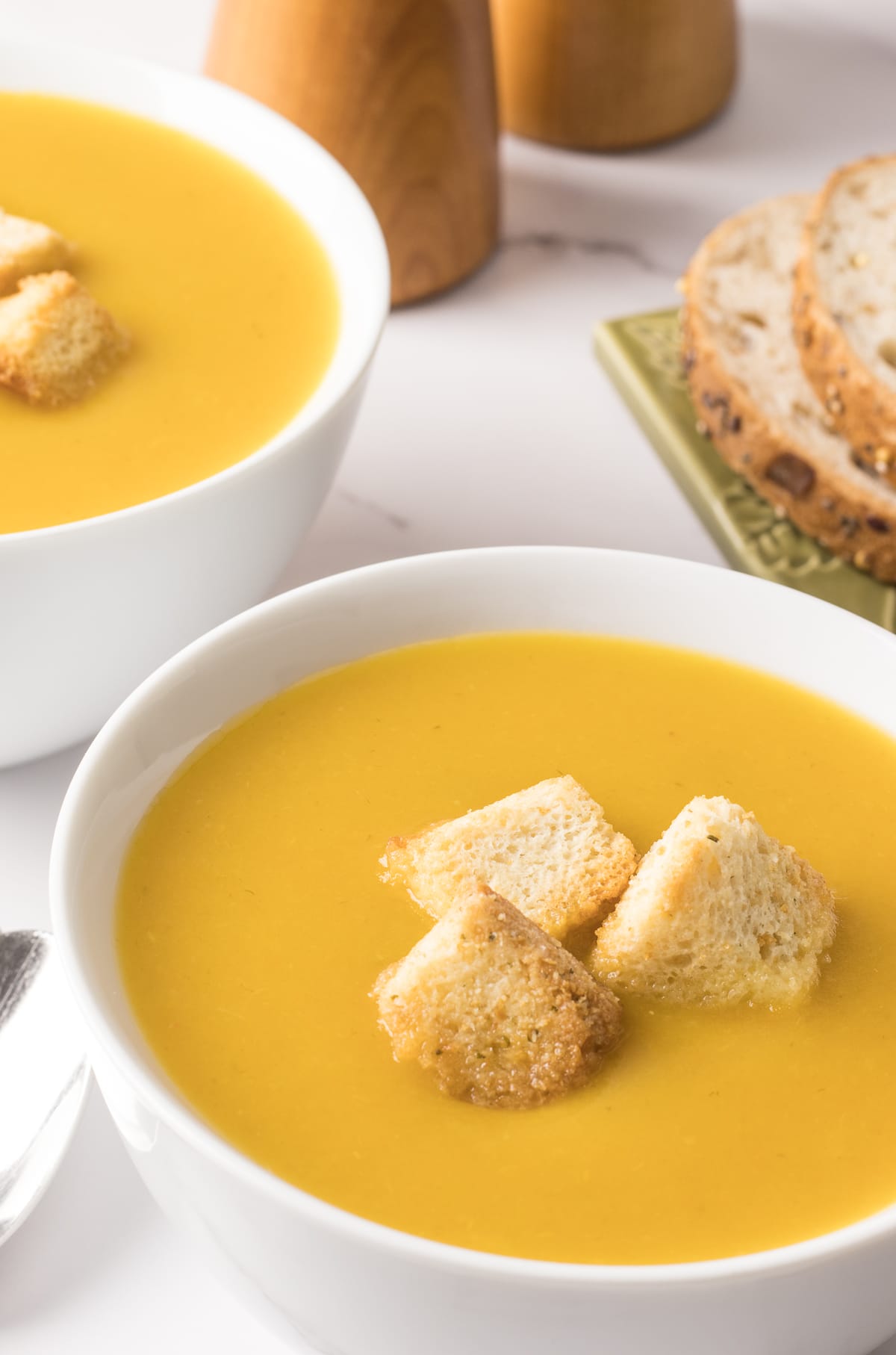 Deux bols remplis de crème de légumes maison avec croûtons et petits pains
