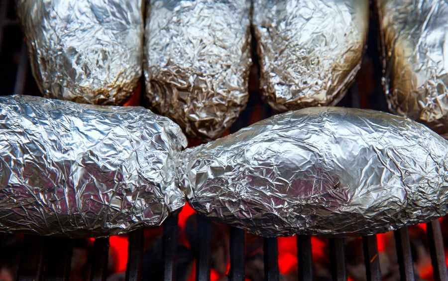 Pommes de terre emballées dans papier d'aluminium qui cuisent sur le barbecue