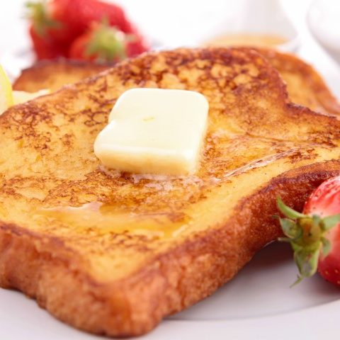Tranche de pain doré avec sirop, beurre et fraises sur une assiette