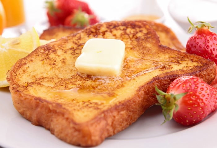 Tranche de pain doré avec sirop, beurre et fraises sur une assiette