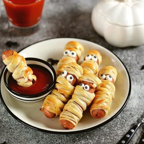 Saucisses à hot-dog enroulées de pâte à croissant pour faire des momies servies avec du ketchup pour l'Halloween