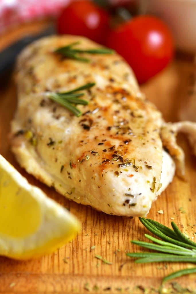 Poitrine de poulet marinée avec une marinade grecque et quartier de citron sur une planche à découper 