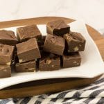 Plusieurs carrés de fudge au chocolat fait au micro-ondes avec du lait Eagle Brand et des noix hachées sur une assiette blanche