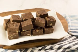 Plusieurs carrés de fudge au chocolat fait au micro-ondes avec du lait Eagle Brand et des noix hachées sur une assiette blanche