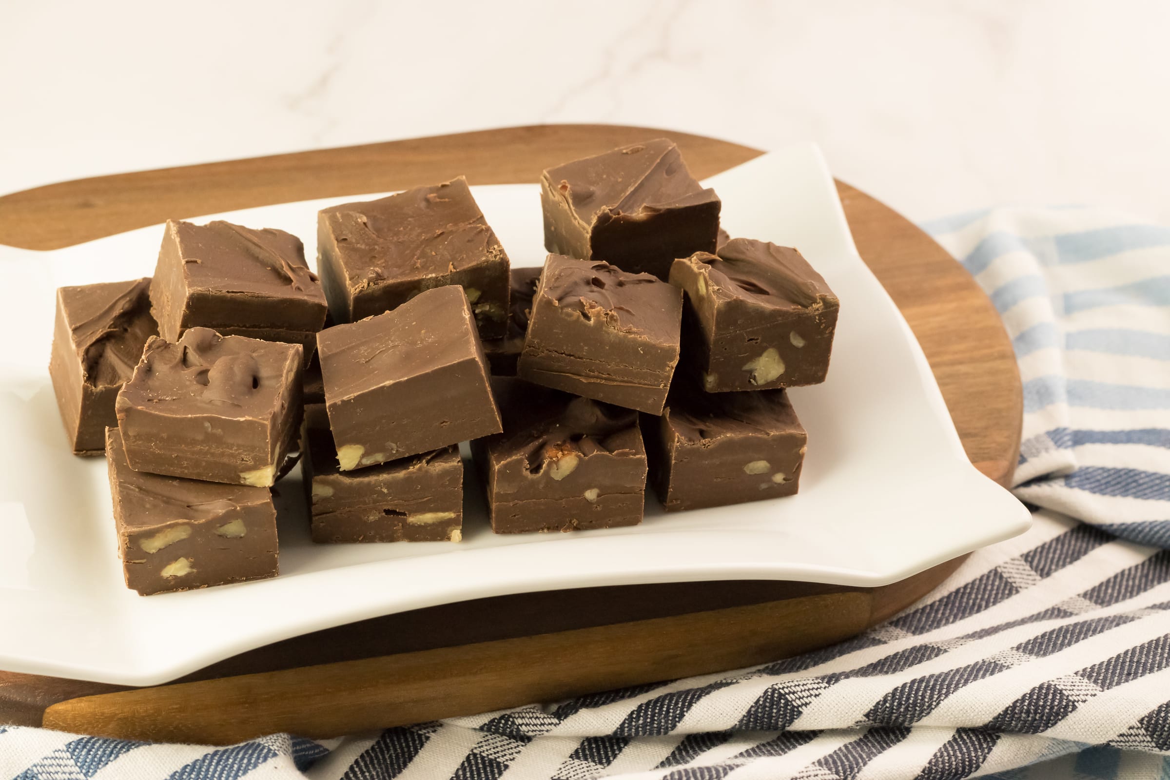 Plusieurs carrés de fudge au chocolat fait au micro-ondes avec du lait Eagle Brand et des noix hachées sur une assiette blanche