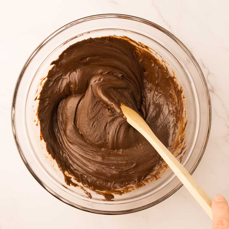 Pépites de chocolat fondus avec lait Eagle Brand qui sort du micro-ondes avec cuillère de bois pour mélanger