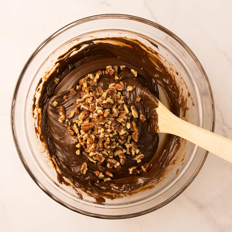 Mélange de fudge au chocolat avec l'ajout de vanille et de noix hachées et mélange avec une grosse cuillère de bois