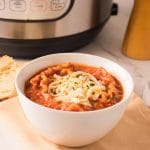 Bol de soupe à la lasagne garni de fromage mozzarella râpé et accompagné de pain.