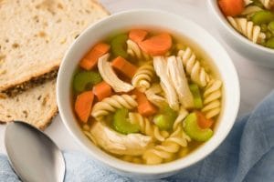Soupe poulet et nouilles maison à l'autocuiseur Instant Pot servi dans deux bols blanc et accompagné de tranches de pain
