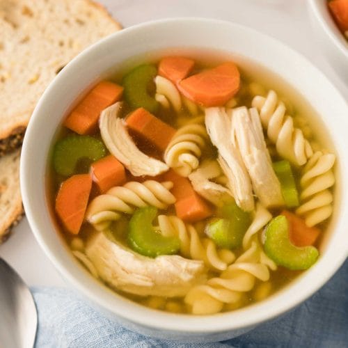 Soupe poulet et nouilles maison à l'autocuiseur Instant Pot servi dans deux bols blanc et accompagné de tranches de pain