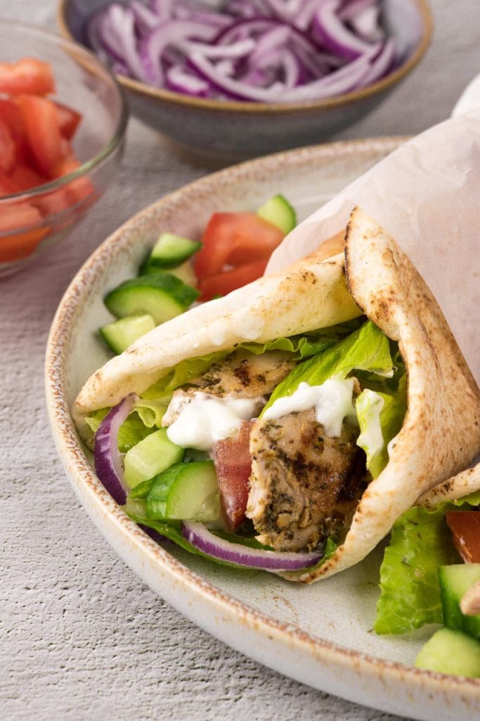 Gyros au poulet grec bien tendre dans un pita avec tomates, concombre, oignons rouges, laitue et sauce tzatziki. 
