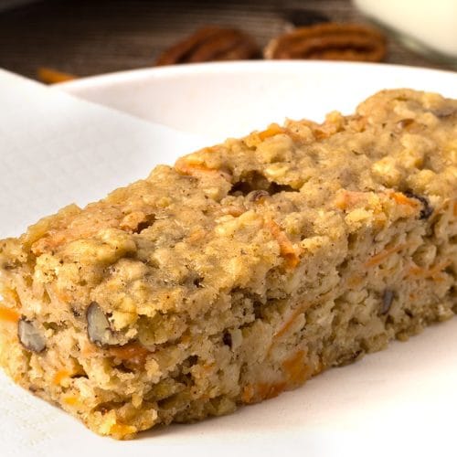 Gros plan d'une barre aux carottes et aux pacanes sur une assiette blanche