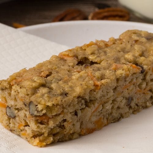 Gros plan d'une barre aux carottes et aux pacanes sur une assiette blanche